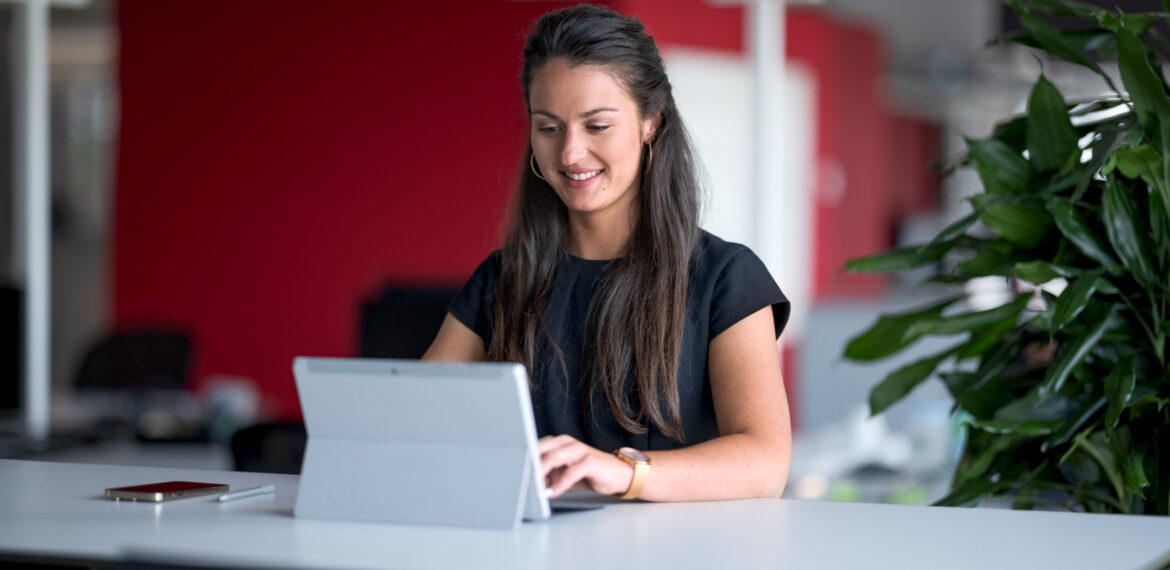 Eine Frau arbeitet in einem Unternehmen am Notebook mit Microsoft Copilot f&uuml;r M365.