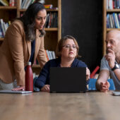 Data governance is essential in the insurance industry (three people having a discussion around a laptop)