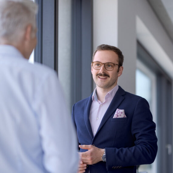 Data Governance für Versicherungen (Zwei Geschäftsmänner im Gespräch vor einem Fenster)