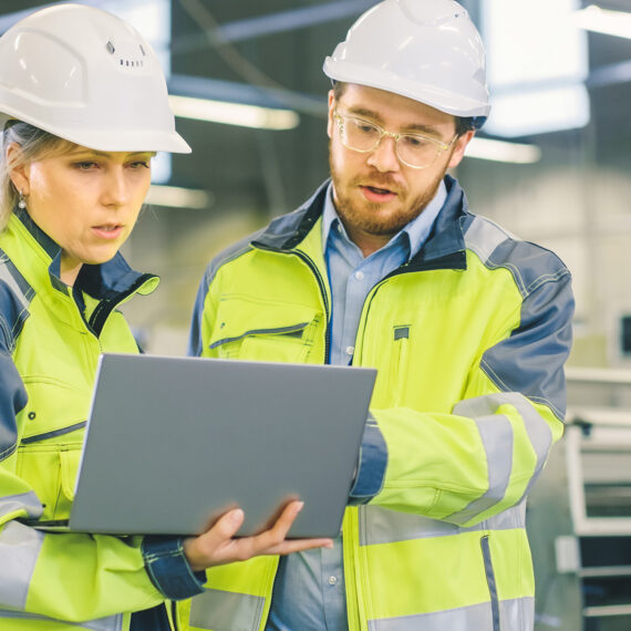 Die Bedeutung von Servitization in der produzierenden Industrie (eine Frau und ein Mann vor einem Notebook in einer Produktionshalle)