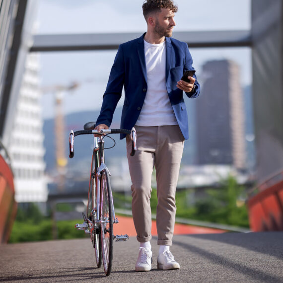 Eine durchdachte AI Governance ist entscheidend, um KI wirkungsvoll im Unternehmen einzusetzen. Interview (Bild: Ein Mann schiebt ein Velo über eine Brücke)