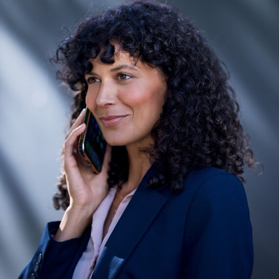 Quels sont les avantages de l’eSIM pour les entreprises? (Une femme en tenue professionnelle téléphone avec un smartphone)