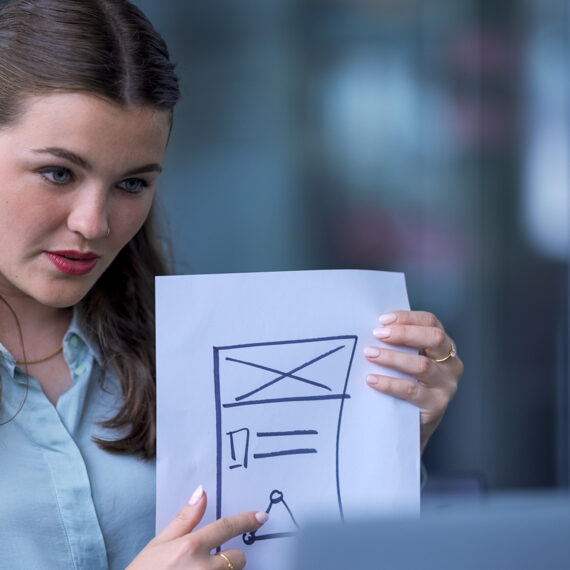 Wie KMU von einem KI-Assistenten profitieren (Frau zeigt Skizze vor Bildschirm)