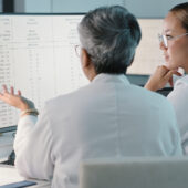 Zwei Frauen aus dem Gesundheitswesen besprechen etwas vor einem Bildschirm