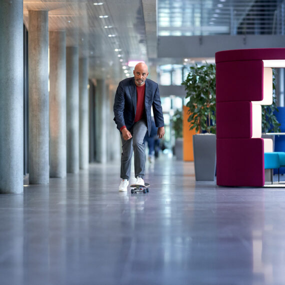 GenAI: Jetzt müssen die Pilotprojekte in Unternehmen liefern (ein Mann fährt auf einem Skateboard durch den Gang eines Bürogebäudes)