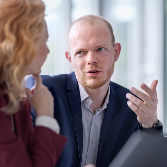 Datensouveränität: Wie behalten KMU die Kontrolle? (Eine Frau und ein Mann diskutieren im Büro vor einem Bildschirm)