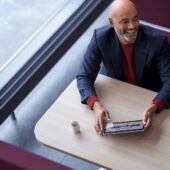 Étude: exigences en matière de Workplace Services et positionnement de Swisscom (homme assis au bureau avec une tablette et un café)